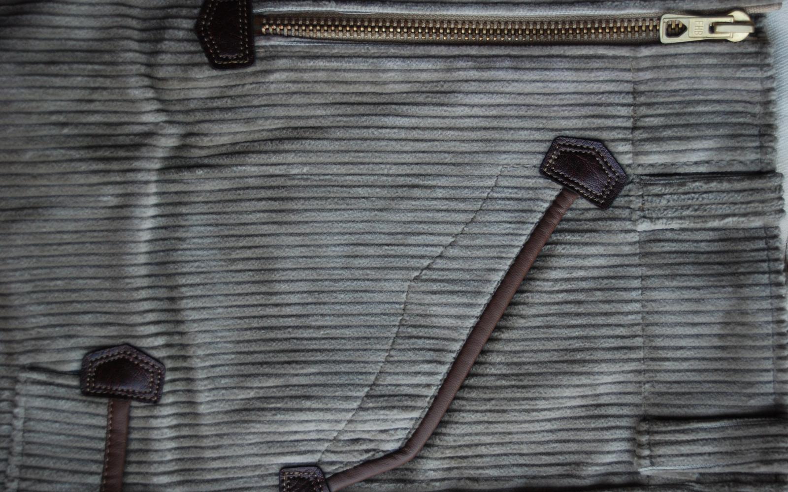 Close-up of a zip and leather pull tabs on corduroy
